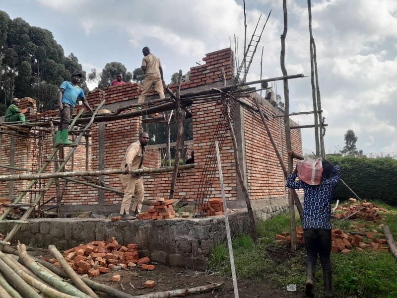 Builders on wooden scaffolding laying bricks on the walls of a new building