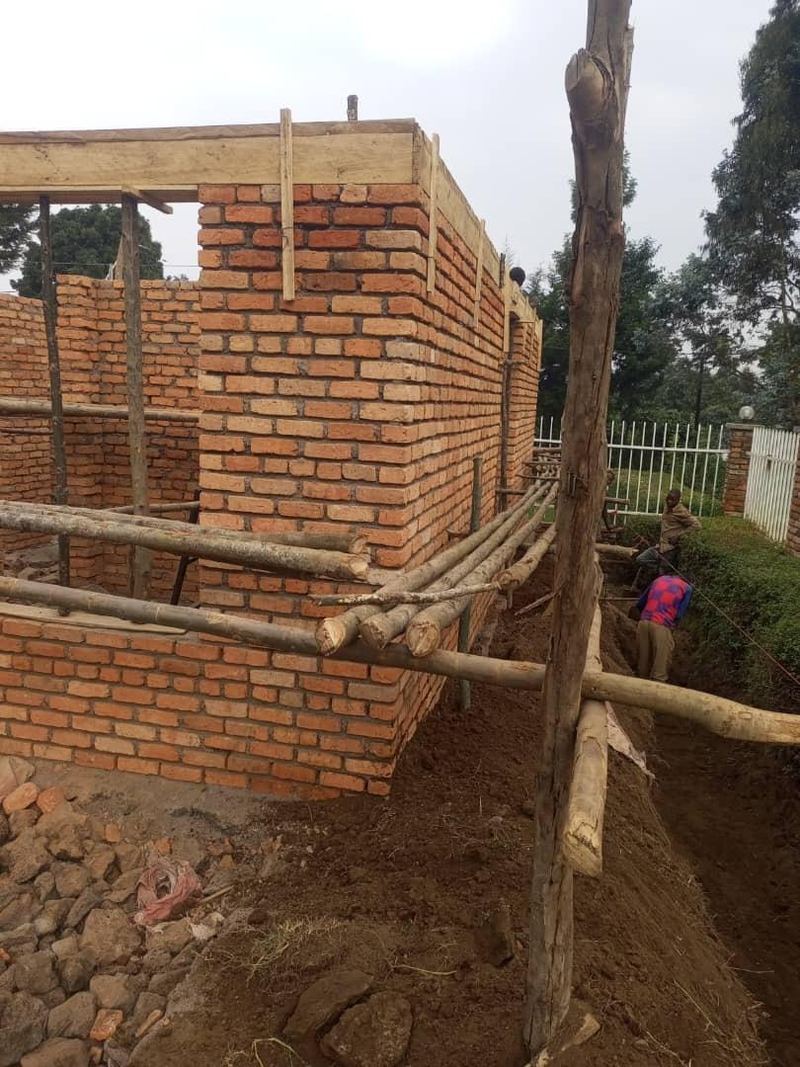 Brick walls of a new building rising behind wooden scaffolding poles