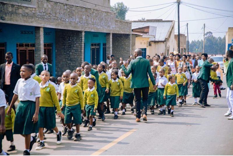 Pupils and adults walking along a street lined with shops