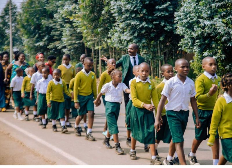 Pupils in yellow jumpers and white shirts walking along a tree-lined road
